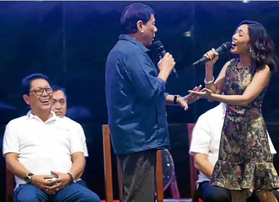  ?? —JOAN BONDOC ?? SINGING CHIEF President Duterte joins Jonalyn Viray in singing his favorite song “Ikaw” during the 84th anniversar­y of the Department of Labor and Employment at the Bulacan provincial gymnasium in Malolos on Friday. Laughing at left is Labor Secretary...