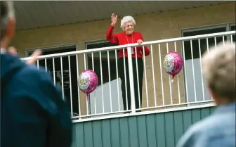  ?? Herald photo by Ian Martens ?? Phyllis Handley waves from an upper-floor balcony to her friends and neighbours as they came out to celebrate her 100th birthday on Wednesday her home at the Grandview Village seniors condo. @IMartensHe­rald