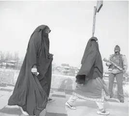  ??  ?? Kashmiri women walk past a paramilita­ry soldier in December in Srinagar.