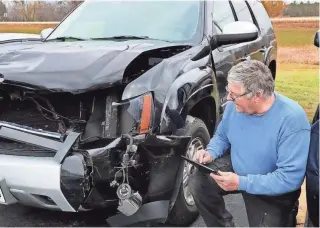  ?? MICHAEL SEARS / MILWAUKEE JOURNAL SENTINEL ?? Todd Gillette, owner of Gillette’s Collision Center in Waukesha, works on a repair estimate for a 2008 Chevy Tahoe. The SUV recently collided with a a white-tailed buck. The SUV's owner, Ryan Hunkins of Mukwonago, said his wife was driving when the buck jumped over a median barrier on I-43 and was struck by the SUV in midair.