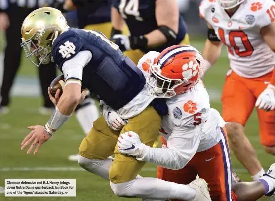  ?? Saturday.
AP ?? Clemson defensive end K. J. Henry brings down Notre Dame quarterbac­k Ian Book for one of the Tigers’ six sacks