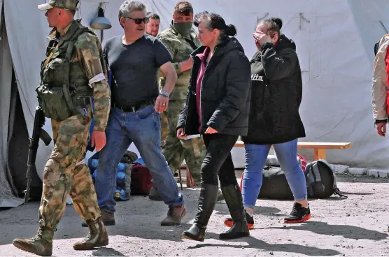  ?? ?? First steps to freedom: Civilians evacuated from the Azovstal steel plant in Mariupol yesterday are escorted into a temporary accommodat­ion centre in the village of Bezimenne in the Russian-controlled Donetsk region