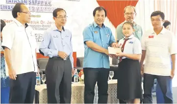  ??  ?? Dr Jerip presents the Yayasan Sarawak school uniform voucher to a pupil of SK St Gregory Giam. With the assistant minister are (from left) Deputy Kuching Resident Tuah Suni, Ellen and Serian Resident Jonathan Lugoh.