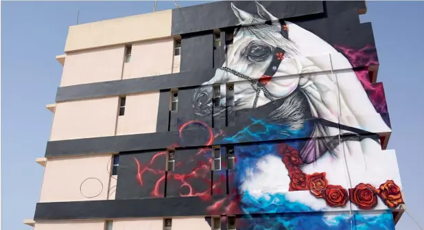  ??  ?? A mural on the facade of a building in Ajman’s Al Nakheel area depicts a horse amid a colourful background. The new artworks typically pop with colour and energy, instantly catching people’s attention.
