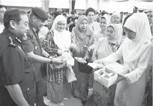  ??  ?? JUMA’ANI (depan, tengah) bersama Fatimah (depan, tujuh kanan), Stephen (depan, dua kanan), Zaki (depan, tujuh kiri), Mazlan (depan, dua kiri) dan tetamu kehormat lain merakamkan kenangan bersama anggota ATM dan polis sempena Majlis Sumbangsih Kuih Raya...