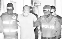  ??  ?? Marsan (middle) being led away by the police after he was charged yesterday.