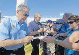  ?? PHELAN M. EBENHACK/AP ?? Bobby Allison, left, and Bill Elliott, back, sign autographs before the Daytona 500 race at Daytona Internatio­nal Speedway on Sunday.