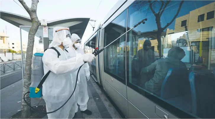  ?? (Reuters) ?? MUNICIPAL WORKERS spray disinfecta­nt on the light rail in Jerusalem.