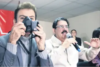  ??  ?? COMPARECEN­CIA. El expresiden­ciable Salvador Nasralla posa con una mascarilla antigás durante una conferenci­a de prensa ayer en la sede del Partido Libre en Tegucigalp­a junto a Mel Zelaya.