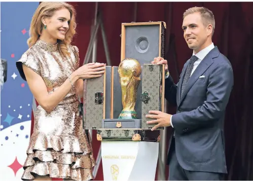  ?? FOTO: DPA ?? Der ehemalige Kapitän, das Model und der Pokal: Philipp Lahm und Natalija Wodjanow präsentier­en die WM-Trophäe in Moskau.