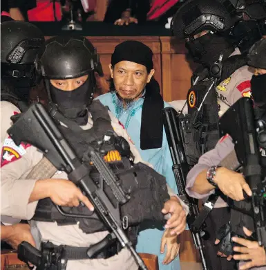  ?? BAY ISMOYO / AFP / GETTY IMAGES ?? Indonesian police officers escort cleric Aman Abdurrahma­n after he was sentenced to death in a Jakarta court Friday.