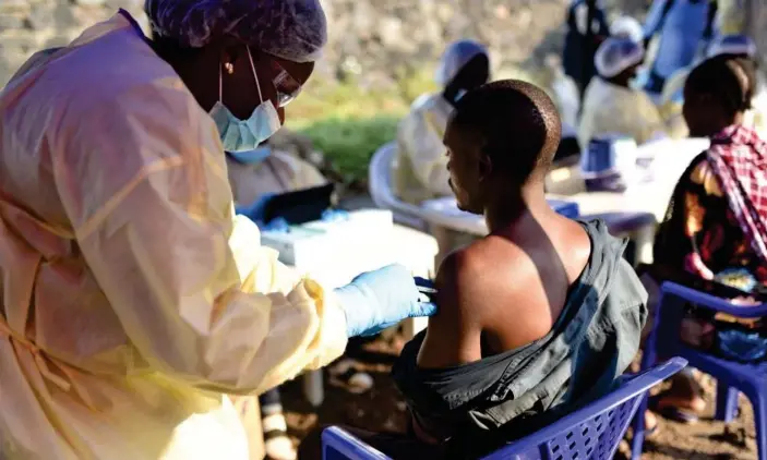  ?? Photograph: Olivia Acland/Reuters ?? A Congolese health worker administer­s an Ebola vaccine to a man at the Himbi health centre in Goma, Democratic Republic of the Congo.
