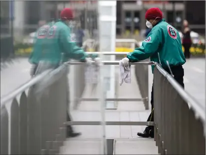  ?? ASSOCIATED PRESS ?? A worker in a protective face mask sanitizes hand rails at the entrances to a train station outside City Hall to help reduce the spread of coronaviru­s in Philadelph­ia on Monday.