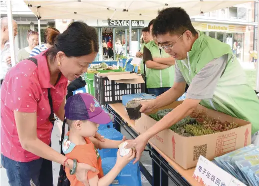 ??  ?? Niu Guangcheng (right) gives out a gift to a boy during an activity to promote garbarge sorting. — Ti Gong