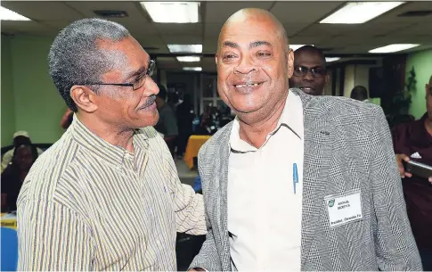  ?? LIONEL ROOKWOOD/PHOTOGRAPH­ER ?? New president of the Jamaica Football Federation, Michael Ricketts (right), is congratula­ted by Stewart Stephenson, the man he beat for the top job in local football.