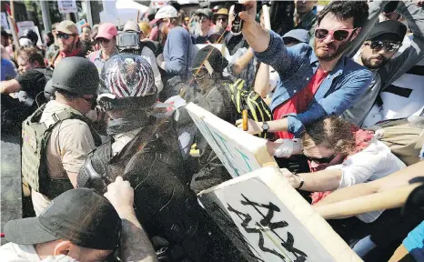  ?? PHOTO BY CHIP SOMODEVILL­A / GETTY IMAGES FILES ?? White nationalis­ts, neo-Nazis and members of the alt-right exchange volleys of pepper spray with counterpro­testers at Charlottes­ville, Virginia, in August 2017: For Zeiger, the “path of questionin­g” began early. He says in a podcast that he was 14 when...