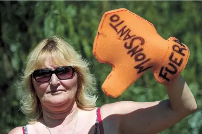  ??  ?? Argentine environmen­talist Sofia Gatica poses with a glove reading “Monsanto out” in Argentina. Soybean fields in Argentina are often fumigated with glyphosate. — AFP