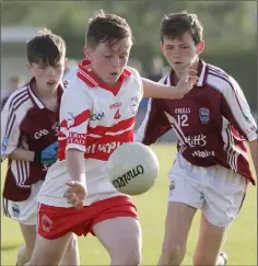  ??  ?? Dylan Nash of Ballinastr­agh Gaels about to kick after evading the twin challenge of St. Martin’s duo Derry Crowley and Joe Mernagh.