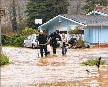  ?? FIREFIGHTE­RS Capt. Tony Freeman Arcata Fire District ?? with the Arcata Fire District help an area resident amid the recent flooding. In unincorpor­ated Humboldt County, dozens of households were still without power Thursday, Pacific Gas & Electric said.