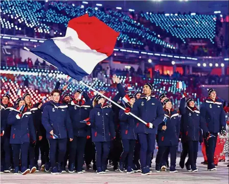  ?? — Reuters ?? Happy to be here: Fourcade carrying the French flag as he marches with his teammates during the opening ceremony at the Olympic Stadium in Pyeongchan­g.