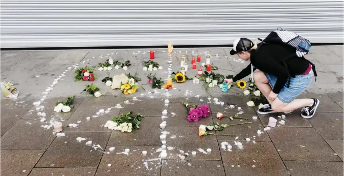  ?? — AFP ?? HAMBURG: A woman places a candle at a makeshift memorial of flowers and candles arranged like a peace sign.