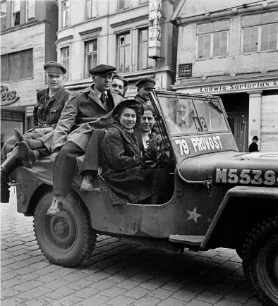  ?? BILD: Getreuenmu­seum/Schlossmus­eum Jever ?? Nach der Befreiung: Kanadische Soldaten fahren mit deutschen Frauen und Männern auf dem Jeep durch die Lange Straße. Im Hintergrun­d der Aufnahme sind die Geschäfte von Leffers und Sartorius zu erkennen.