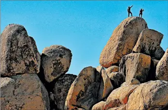  ?? MARIO TAMA/GETTY ?? Rock climbers stand Friday on top of a formation at Joshua Tree National Park, which has remained open during the shutdown. Campground­s at the California park have closed.