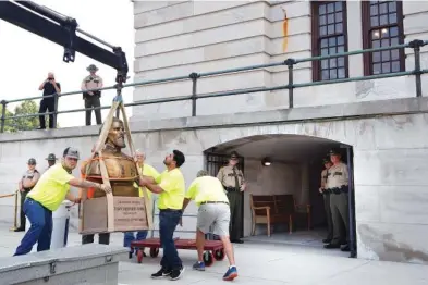  ?? PHOTOS BY GEORGE WALKER IV /THE TENNESSEAN VIA AP ?? Workers remove the Nathan Bedford Forrest bust from the State Capitol as State Troopers stand guard Friday in Nashville. The State Building Commission on Thursday gave approval for the relocation of the Forrest bust to the Tennessee State Museum, a final step in a process that has taken more than a year since Gov. Bill Lee first said it was time for the statue to be moved.