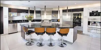  ??  ?? The kitchen is sleek and modern with some retro overtones and has high-end lighting treatments.
