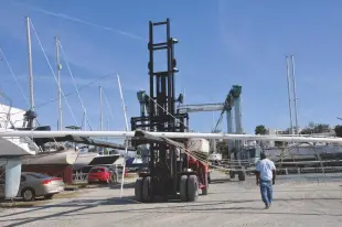  ??  ?? The forklift truck carried the masts to trestles already set up in the boatyard