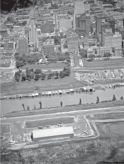  ?? THE COMMERCIAL APPEAL FILES ?? This aerial view of Downtown Memphis, dating to 1958, shows Mud Island with its small airport and the Wolf River Harbor in foreground. The skyline contained the Claridge Hotel, the King Cotton Hotel, the Falls Building, the U.S. Court House, the...