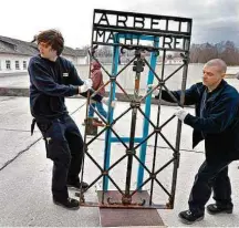  ?? Uwe Lein/AFP ?? » DE VOLTA Operários carregam o portão do campo de concentraç­ão de Dachau (Alemanha) com o slogan nazista ‘o trabalho liberta’; item havia sido roubado há dois anos