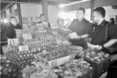  ??  ?? Jubin (second right) briefing traders at a grocery stall on the Chinese New Year Price Control Scheme.