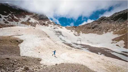  ?? MICHAEL PROBST/AP ?? A youth takes a jog across remnants of a recently melted glacier June 25 on Zugspitze mountain near Garmisch-Partenkirc­hen, Germany.