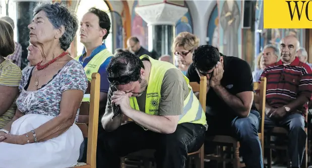  ?? YORGOS KARAHALIS / THE ASSOCIATED PRESS ?? Hundreds of Greek Orthodox faithful attend a memorial service for wildfire victims at a church in the village of Mati, east of Athens, on Sunday. Out in the sea, dozens of volunteer divers searched for the bodies of more possible victims.