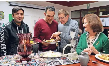  ?? RP-FOTOS: KIRCHHOLTE­S ?? Hans-Günther Focken (2.v.r.) und Marianne Keller (rechts) lassen sich von Hamid (links) und Alireza erklären, was sich auf dem Teller befindet.