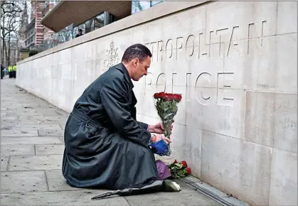  ??  ?? A simple tribute marking Wednesday’s attack: a man lays a bunch of flowers outside New Scotland Yard yesterday