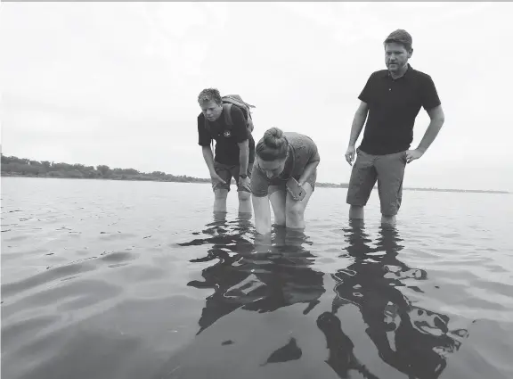  ?? PHOTOS: JEAN LEVAC ?? Andrew King, left, and archaeolog­ists Nadine Kopp and Ben Mortimer of the Paterson Group, look at a possible shipwreck found in the Ottawa River in early August.