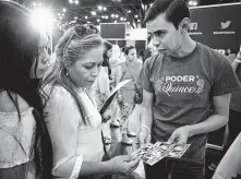  ?? Melissa Phillip / Staff file photo ?? Julie Tovar, 16, and her mother, Carina, talk with Antonio Arellano of voter registrati­on group Poder Quince on Aug. 4 at the George R. Brown Convention Center.