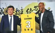  ?? WEI XIAOHAO / CHINA DAILY ?? Stephon Marbury and Wang Jinshan, president of the Beijing Rural and Commercial Bank, pose with a Beikong Fly Dragons jersey after announcing the former NBA star’s $1.3-million contract with the CBA team on Sunday in Beijing.