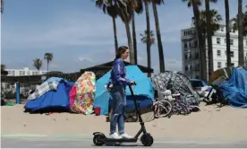  ??  ?? A woman rides past homeless encampment­s on a bike path in Los Angeles. Photograph: Lucy Nicholson/Reuters