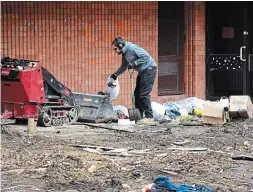  ??  ?? A worker cleans up garbage left after a homeless camp was dismantled Monday night in front of the former Sir John A. Macdonald school.