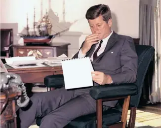  ?? HENRY BURROUGHS/THE ASSOCIATED PRESS FILES ?? In this Jan. 18, 1962 photo, U.S. president John F. Kennedy looks over notes at his desk in the White House.