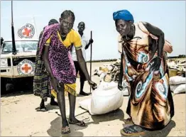  ?? ALBERT GONZALEZ FARRAN/GETTY-AFP ?? Women on Tuesday drag a sack of seeds distribute­d by the Red Cross in South Sudan.