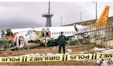  ?? FOTO: DPA ?? Ein Polizist bewacht das Wrack eines Pegasus-Flugzeugs. Es war bei der Landung von der Piste abgekommen und in drei Teile zerbrochen.