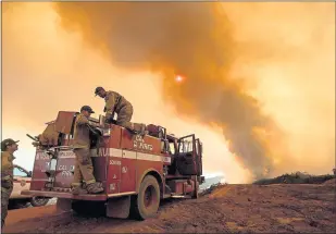  ?? GETTY IMAGES ?? Firefighte­r Joe Smith retrieves supplies while battling the Ranch Fire, part of the Mendocino Complex Fire, burning along High Valley Road near Clearlake Oaks.