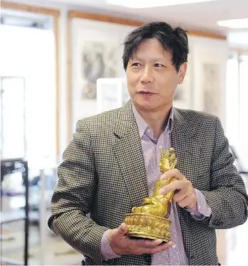  ?? NICK PROCAYLO ?? Jade d’Art chief executive and appraiser Dichen Hu displays a Ming gilded-bronze Buddha dating back more than 600 years. Valued at $250,000, the statue could fetch as much as $1 million in today’s auction.