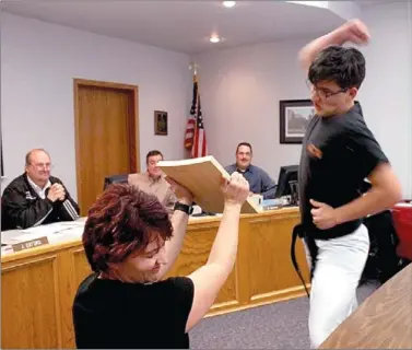  ?? LYNN KUTTER ENTERPRISE-LEADER ?? Farmington eighth-grader Joey Broadway demonstrat­es which Taekwondo move is the best for breaking a piece of wood at the March 23 School Board meeting. His mother, Marilyn Soukep, turns her head in anticipati­on of the hit.