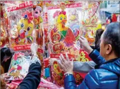  ?? ISAAC LAWRENCE/AFP ?? People browse at a stall in Hong Kong selling decoration­s for the Year of the Rooster.