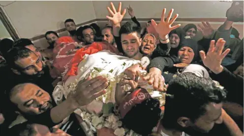  ?? MAHMUD HAMS AGENCE FRANCE-PRESSE ?? Les proches de Mohammed Ouda, tué par une attaque aérienne israélienn­e lundi, ont couvert son corps de fleurs pour ses funéraille­s, à Beit Lahia dans la bande de Gaza. En moins de vingt-quatre heures, au moins sept Palestinie­ns ont été tués et vingt-six blessés par la riposte israélienn­e aux centaines de roquettes tirées de Gaza, qui ont fait un mort et des dizaines de blessés en territoire israélien.